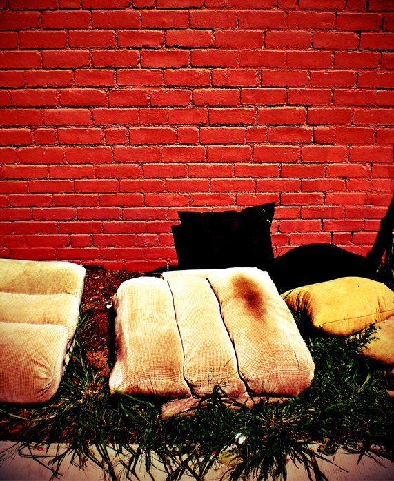 Photograph by Craig Witte highlighting the contrast of discarded items against city architecture.